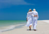 Rear View Of Senior Couple Walking On Beach