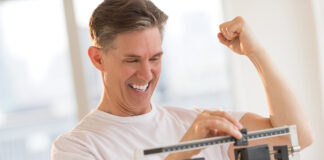 Excited Man Clenching Fist While Using Weight Scale