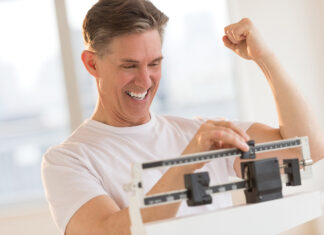 Excited Man Clenching Fist While Using Weight Scale