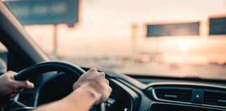 Hand Of Man Driving Car On The Road.