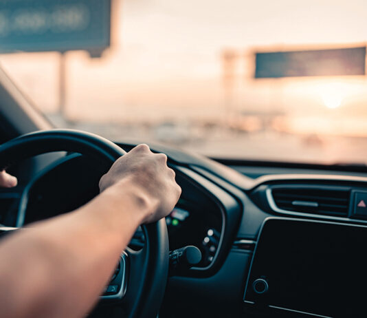 Hand Of Man Driving Car On The Road.