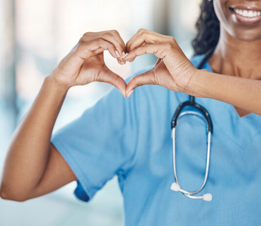 Closeup African American Woman Nurse Making A Heart Shape With Her Hands While Smiling And Standing In Hospital. Take Care Of Your Heart And Love Your Body. Health And Safety In The Field Of Medicine