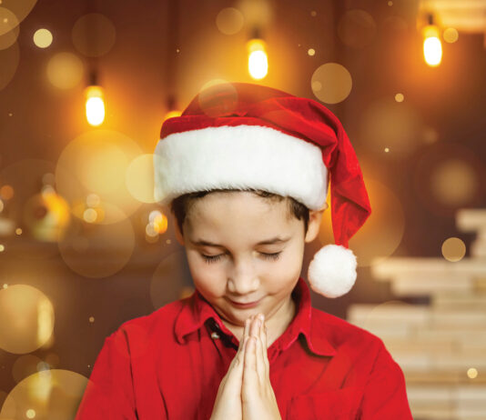 Praying child in Christmas hat