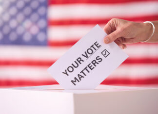 Hand Placing Ballot In Box With American Flag