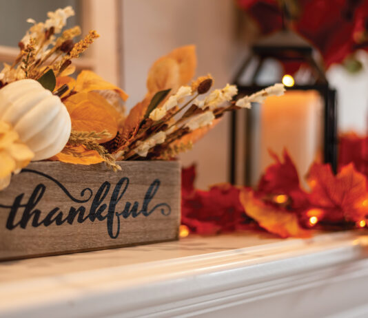 Fall Holiday Mantel Decorated With Colorful Leaves And Twinkle Lights