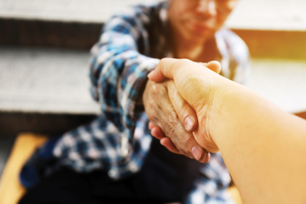 Close Up Handshake For Help Homeless Man On Walking Street In The Capital City.