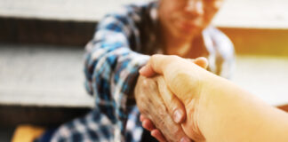 Close Up Handshake For Help Homeless Man On Walking Street In The Capital City.