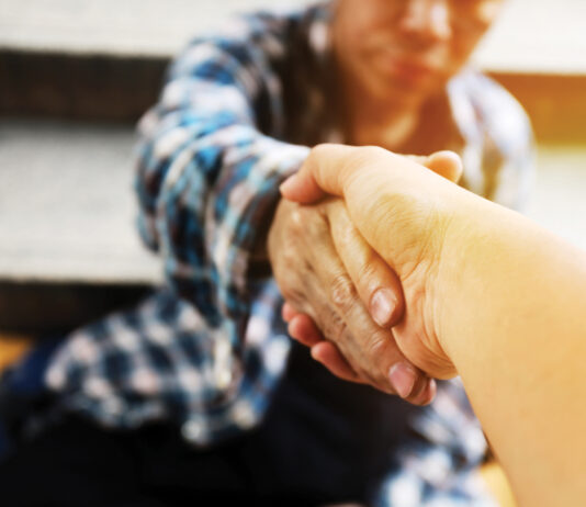 Close Up Handshake For Help Homeless Man On Walking Street In The Capital City.