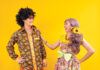 Asian Hippie Couple Dress In 80s Vintage Fashion With Colorful Retro Clothing While Dancing Together Isolated On Yellow Background For Fancy Outfit Party And Pop Culture