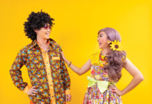 Asian Hippie Couple Dress In 80s Vintage Fashion With Colorful Retro Clothing While Dancing Together Isolated On Yellow Background For Fancy Outfit Party And Pop Culture