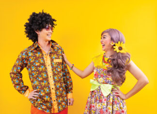 Asian Hippie Couple Dress In 80s Vintage Fashion With Colorful Retro Clothing While Dancing Together Isolated On Yellow Background For Fancy Outfit Party And Pop Culture